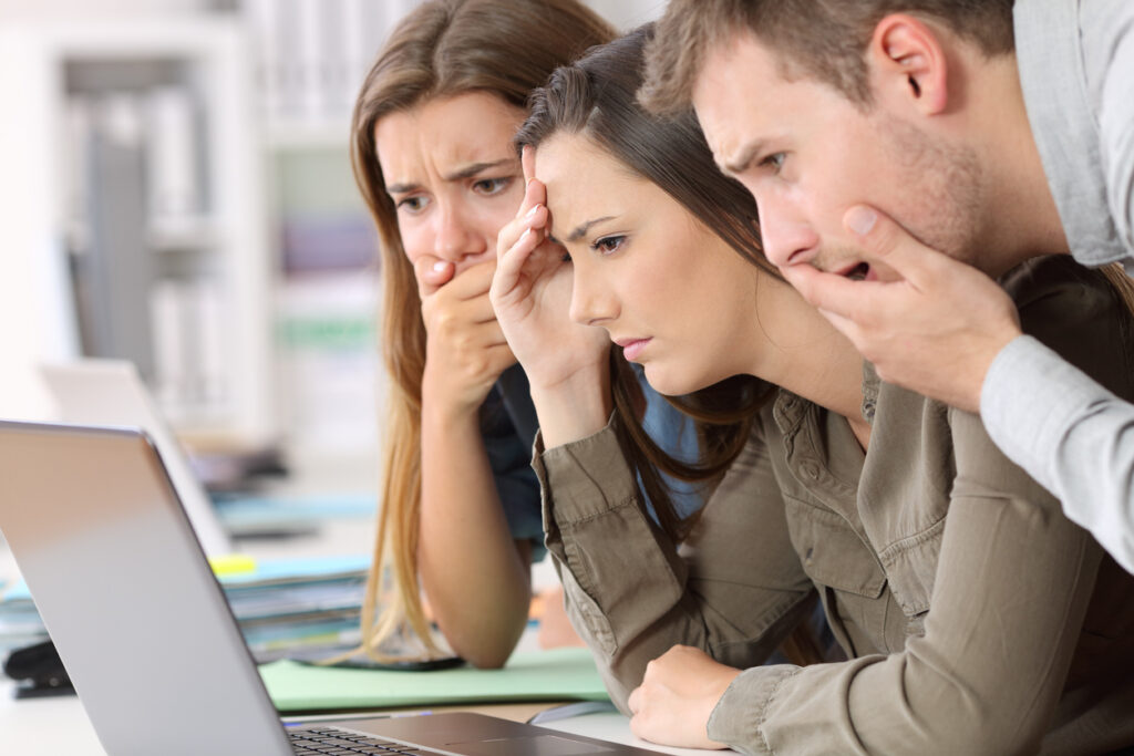 Three employees looking into a computer screen looking shocked while figuring out why knowledge management fails