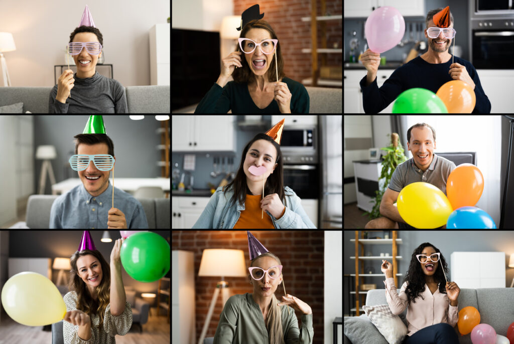 A group of remote employees meeting through Zoom and holding or wearing party materials, showing that relationships among global teams can be formed through fun virtual activities.
