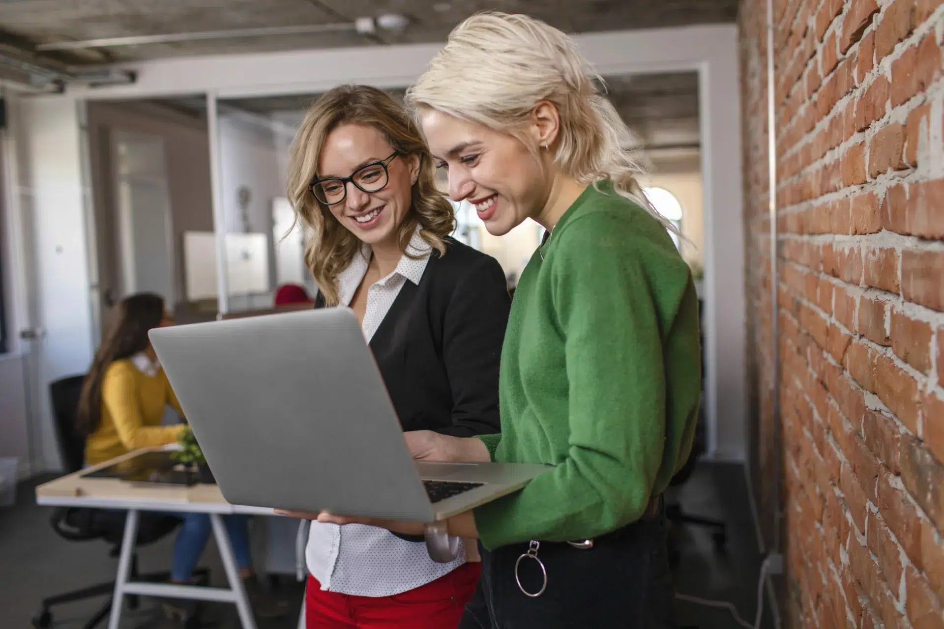 good client-agency relationship shown by two employees standing with laptop