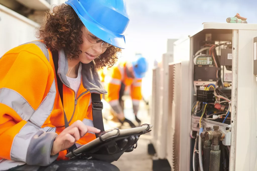 field service representatives check tablet while repairing AC unit