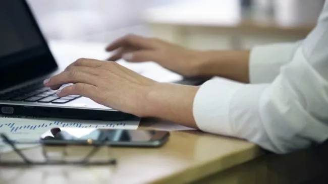 hands of office worker entering data from post-launch surveys on laptop