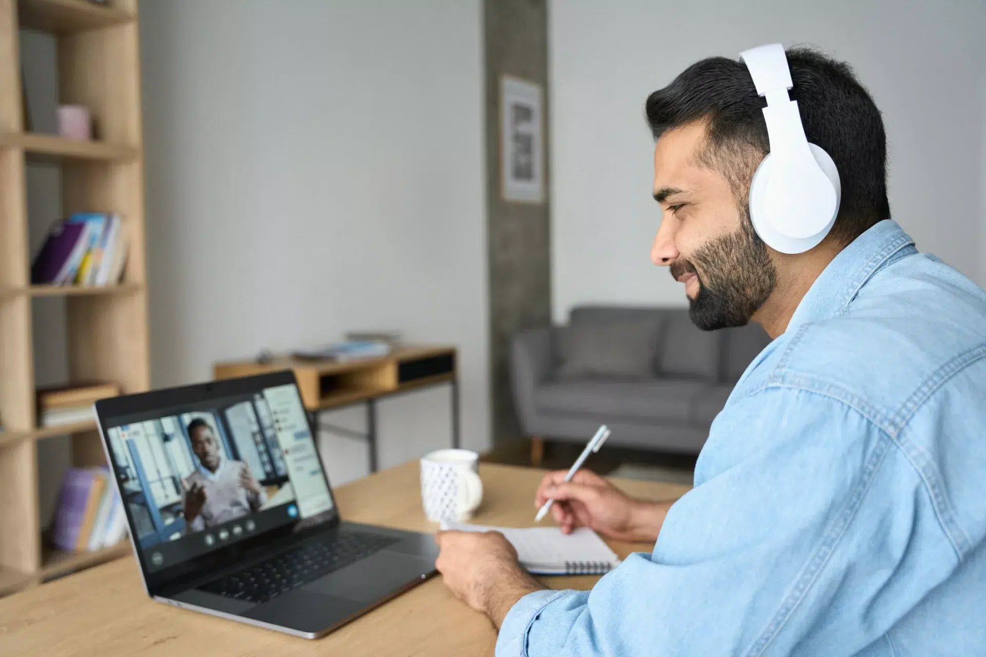 remote employee watching video on laptop and taking notes