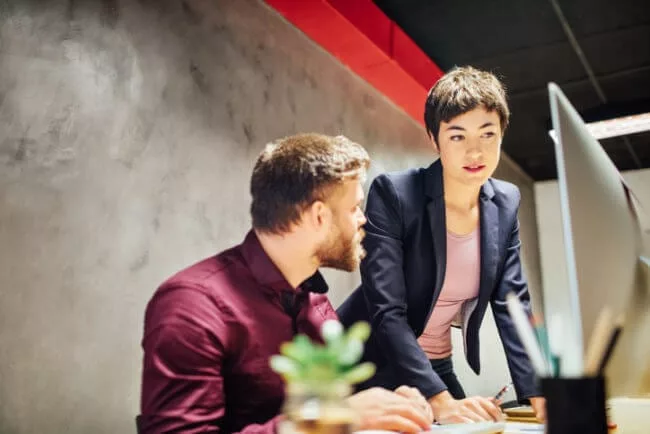 Sales and customer success team members meet at desk