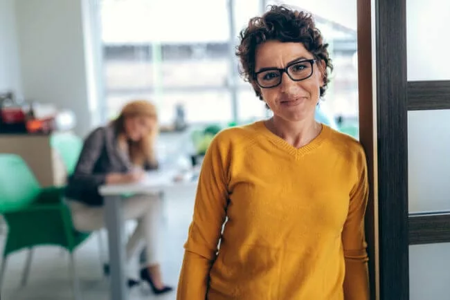 smiling manager with empowered employee in background; happy about employee independence