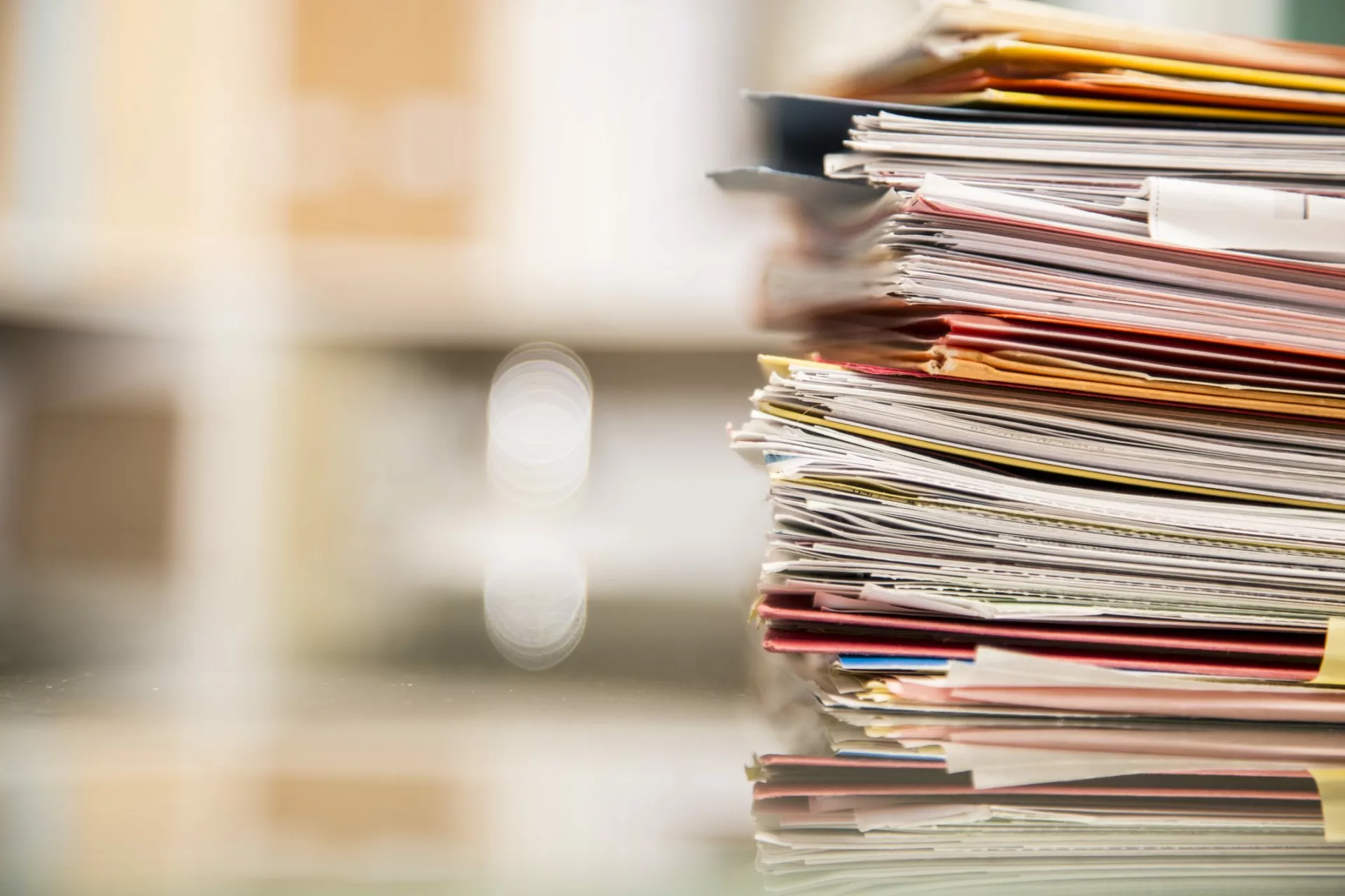 stack of folders on desk suggest it's time to upgrade knowledge management strategy