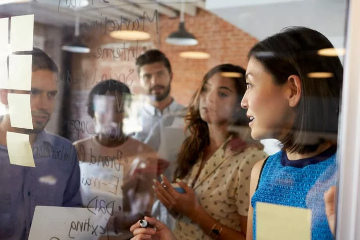 business team writing ideas on glass showing need for knowledge sharing platform for startups