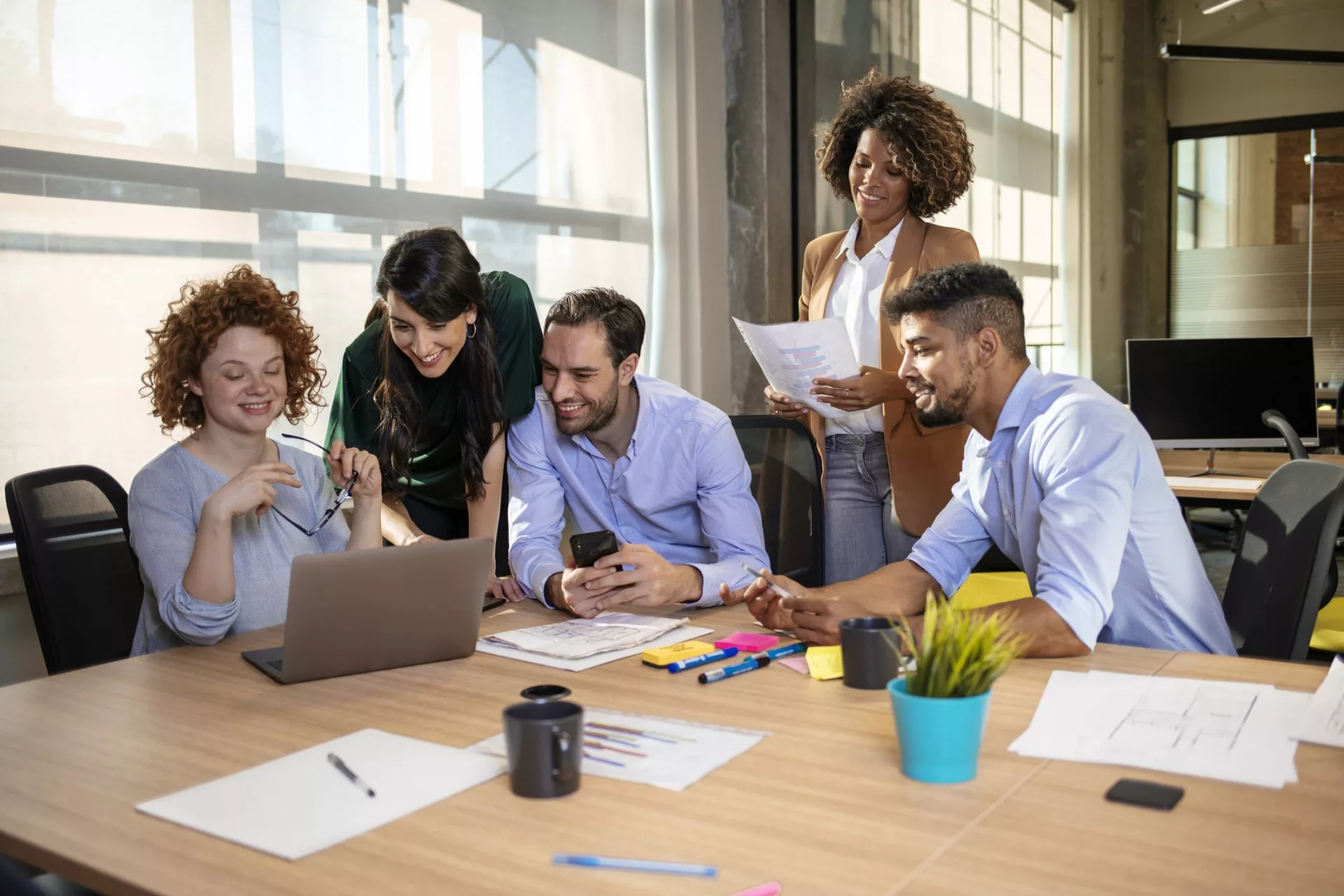 team gathers around laptop to plan knowledge management platform launch