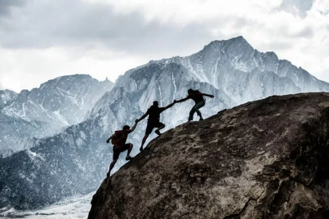friends helping each other mountain climbing representing trustworthy content