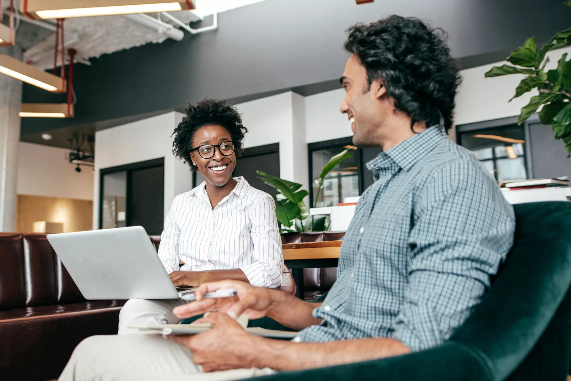 two coworkers having an informal meeting with a laptop and notebook demonstrating examples of companies using knowledge management