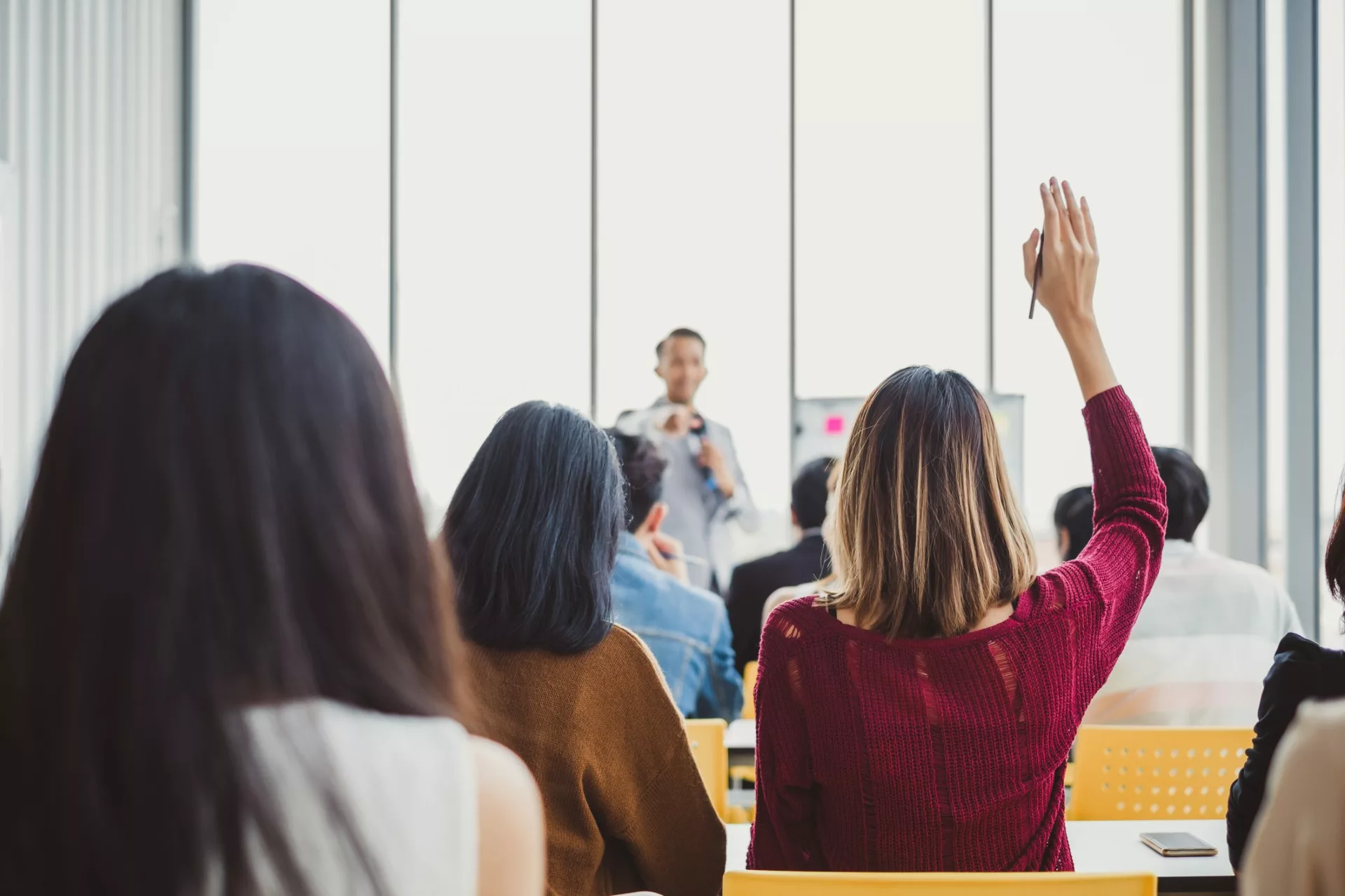 woman raising hand in training session representing concept of cost of training employees