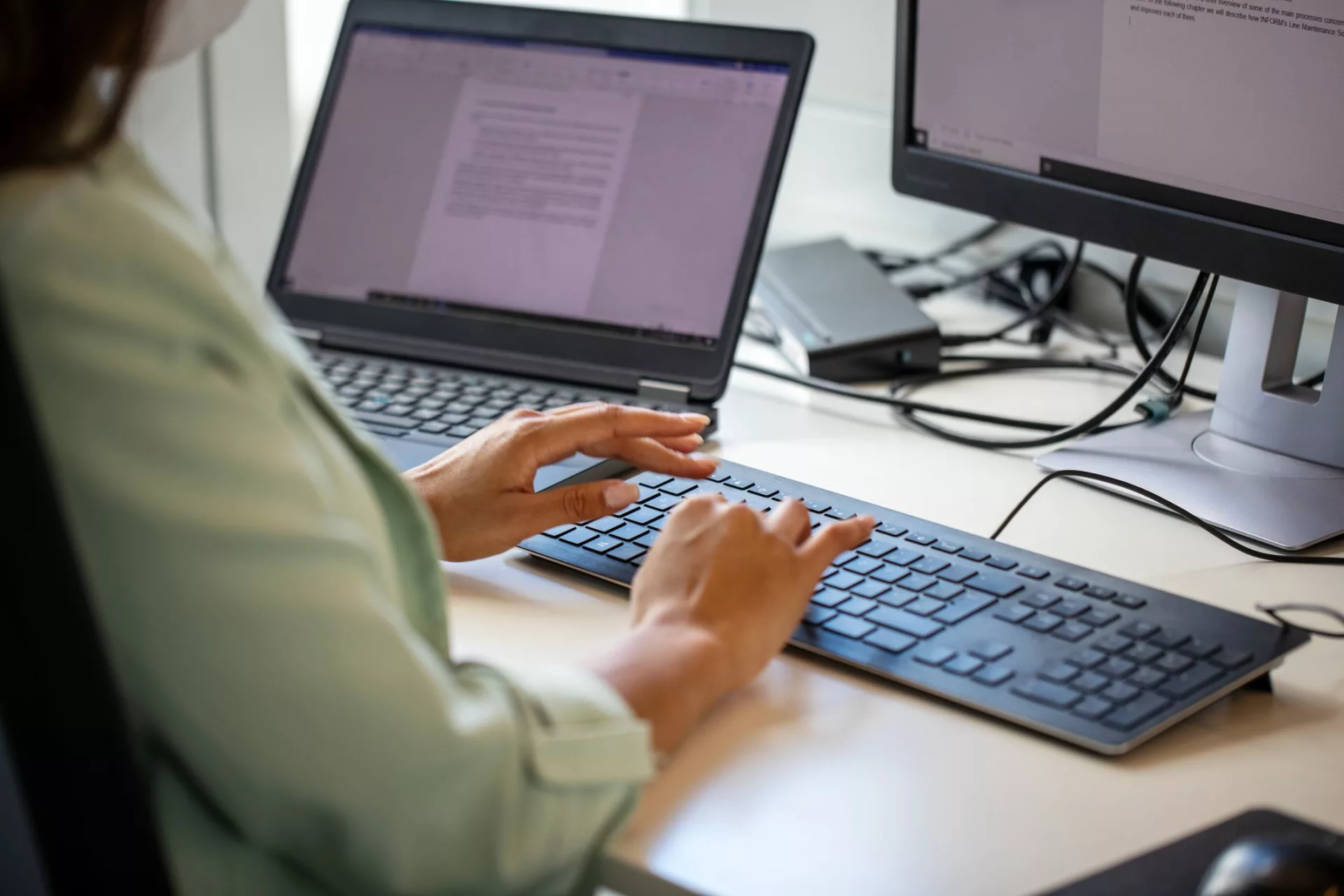 woman typing in word processor representing content management vs. knowledge management