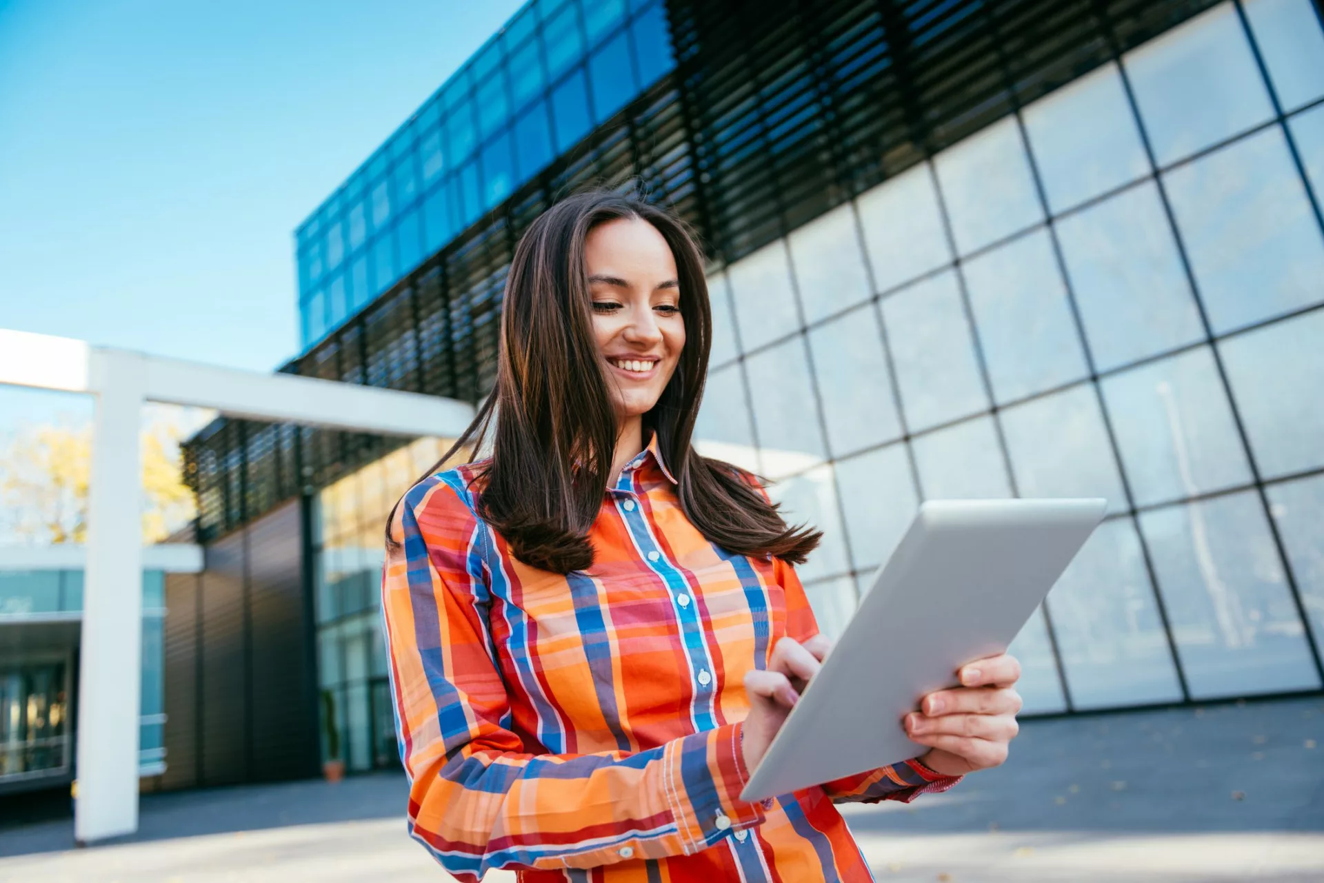 woman outside of modern office looks up information on tablet