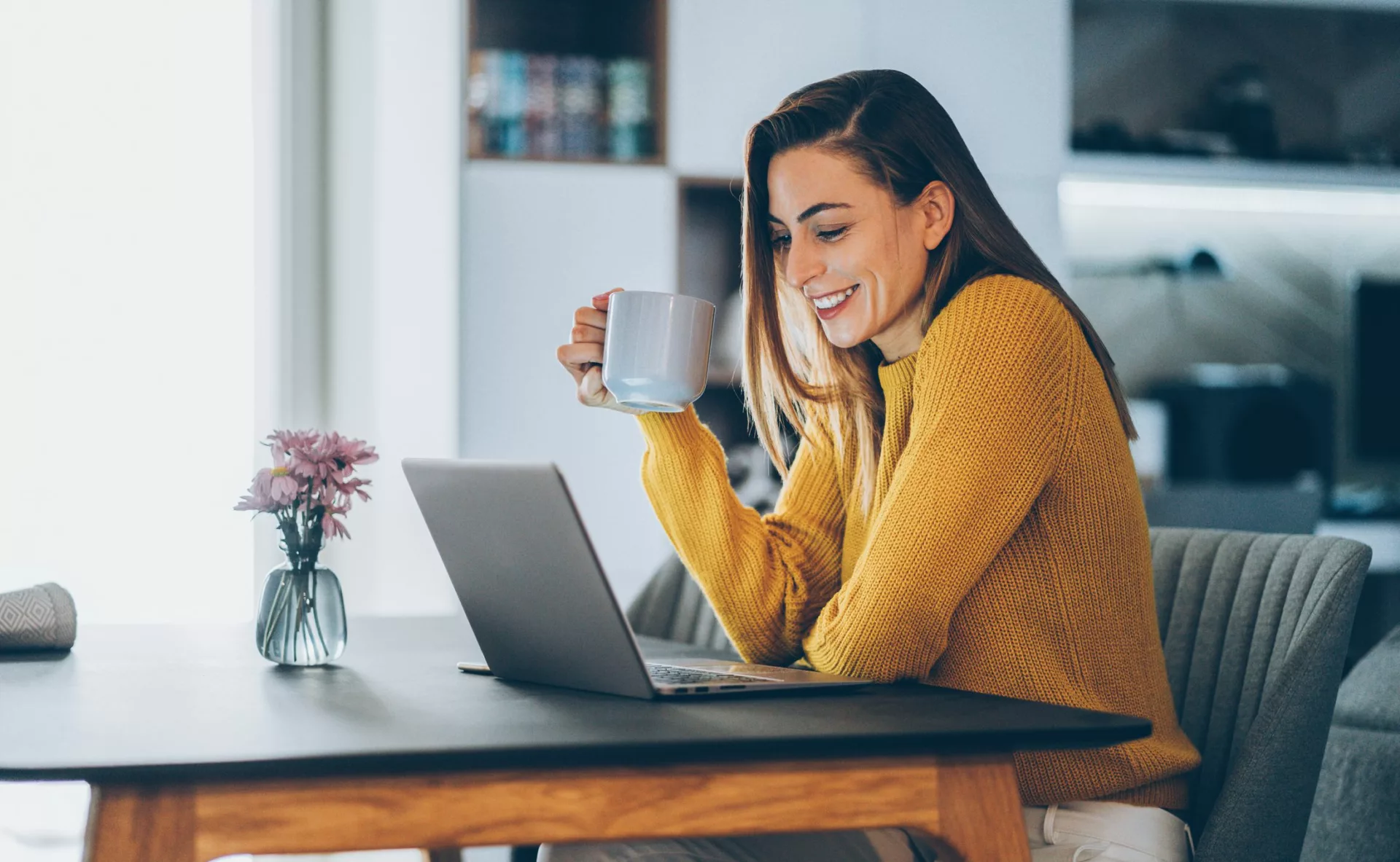 Woman working from home on laptop, illustrating what a knowledge base is and enjoying the benefits of a knowledge base for productivity and collaboration.