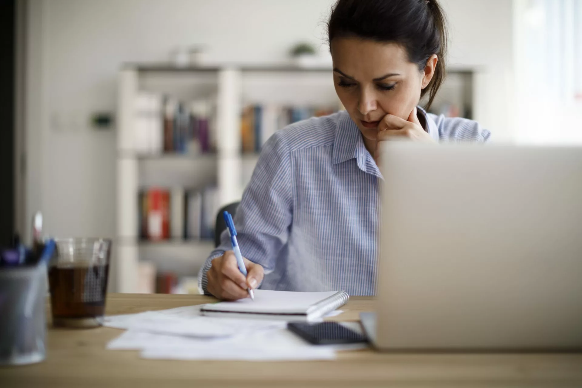 woman at laptop taking notes to prevent knowledge silos