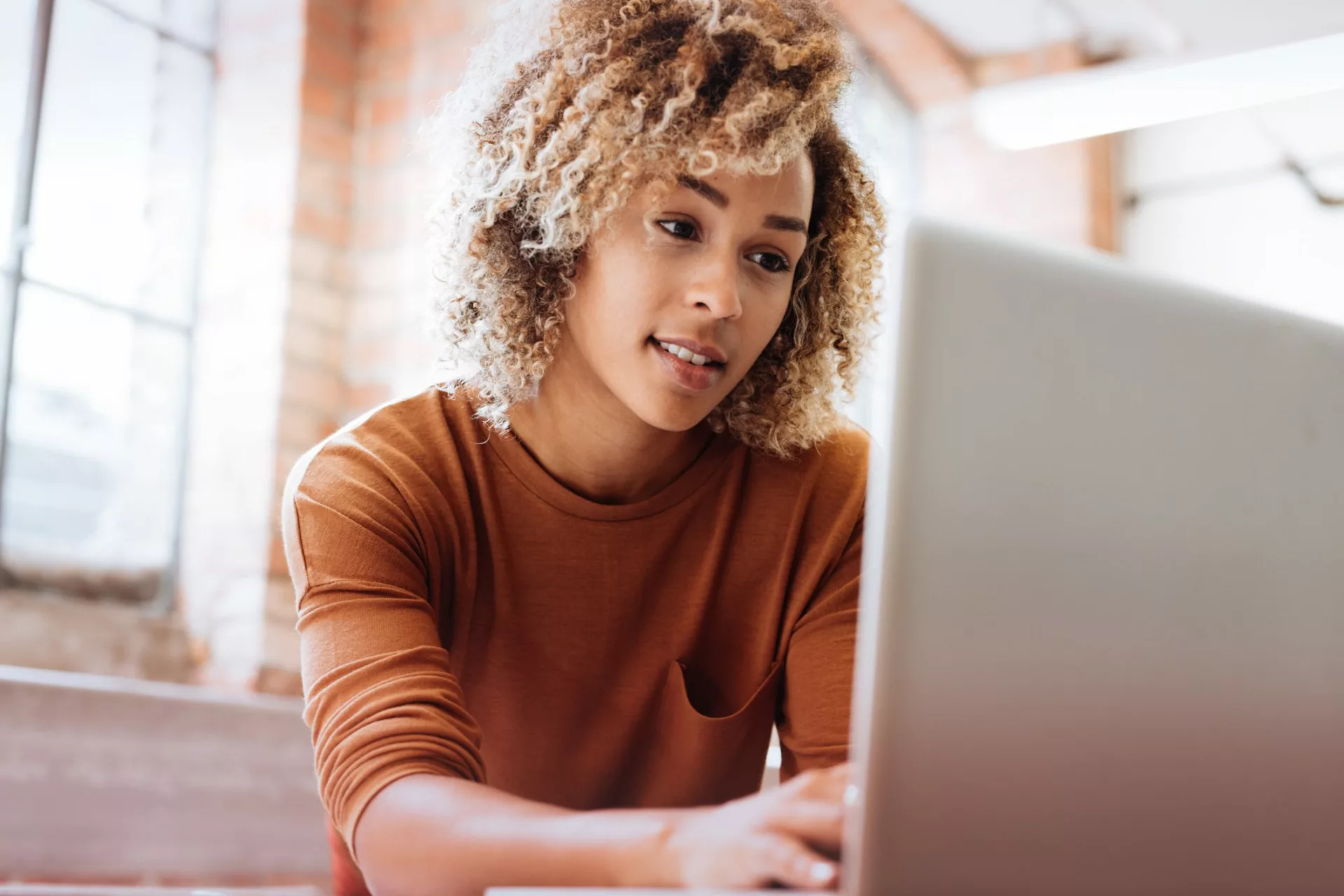 woman in orange shirt at laptop improves her digital dexterity