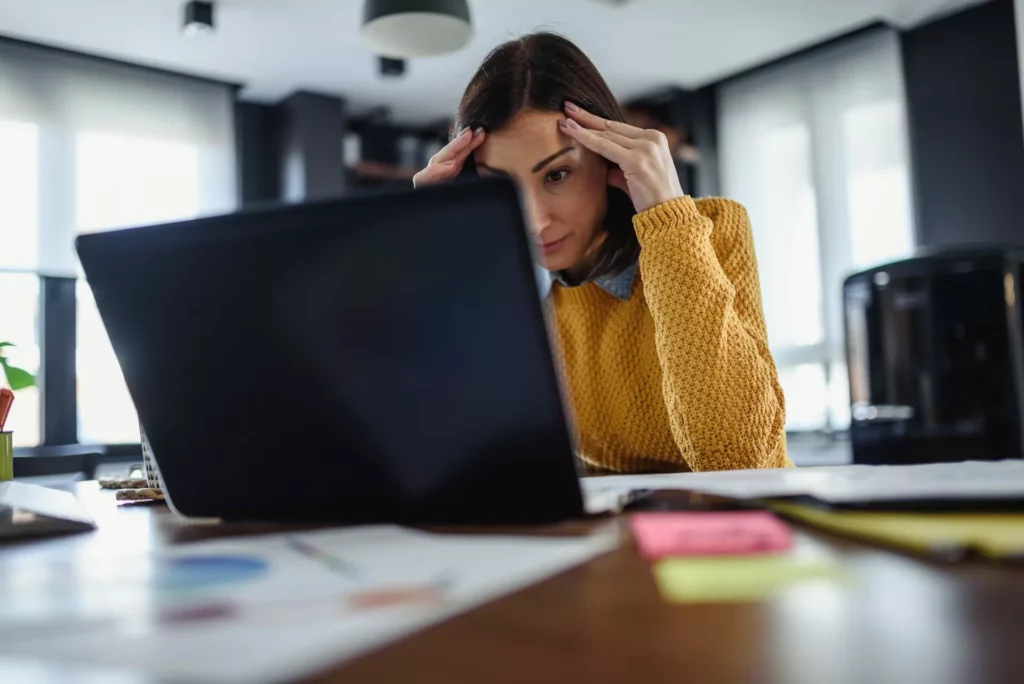 woman at laptop frustrated by high cost of outdated knowledge management solution