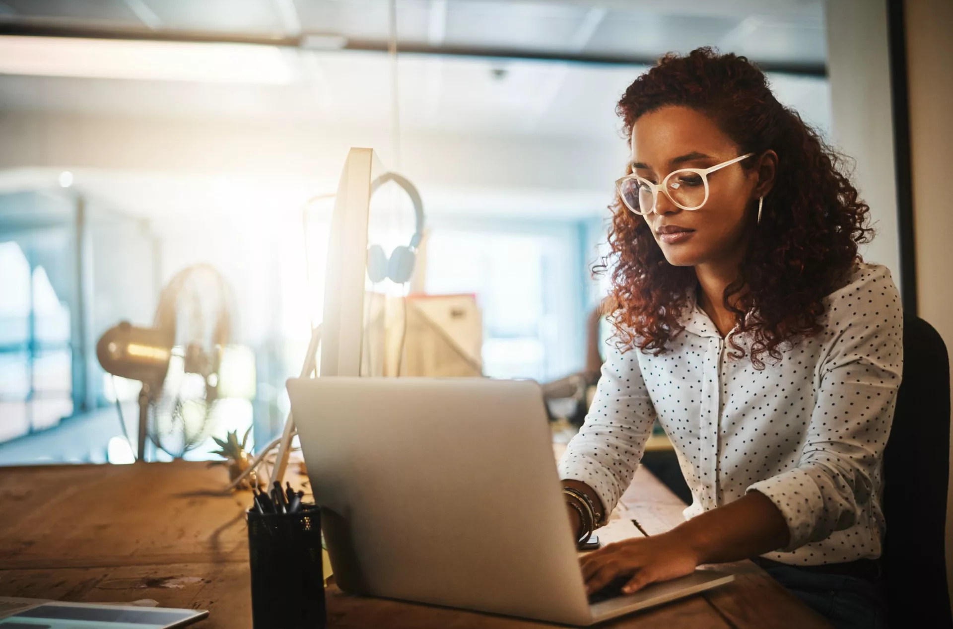 woman focusing on laptop alone in office represents knowledge hoarding