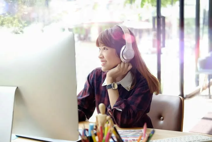 woman with headphones watching onboarding videos on computer