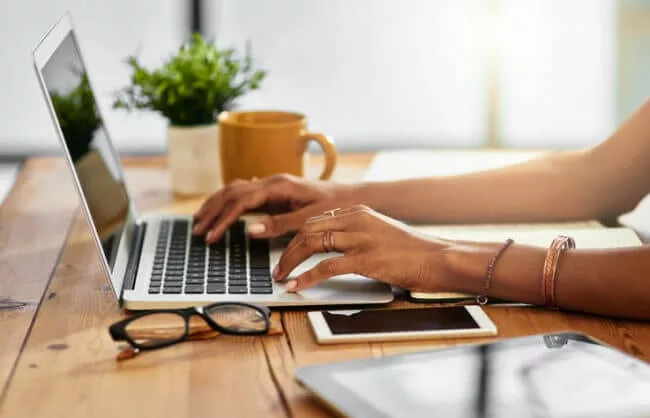 shot of woman typing on laptop possibly evaluating Bloomfire vs. SharePoint