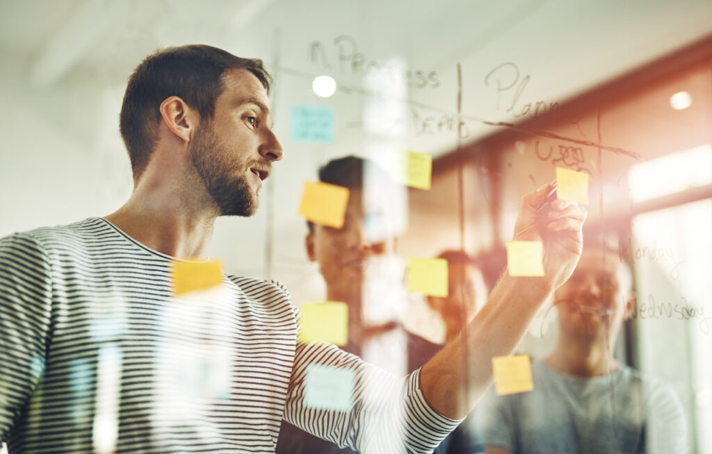 A team of organizational leaders using sticky notes to plan their knowledge management implementation, including setting knowledge management goals and objectives