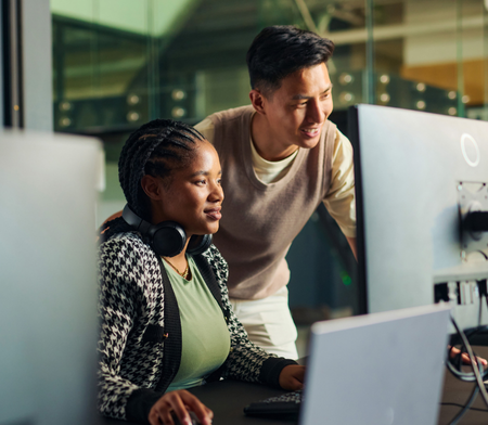 Two colleagues looking at a large desktop computer screen