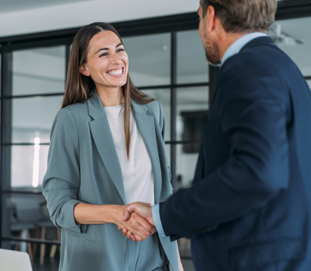 Female and male colleague shaking hands and smiling