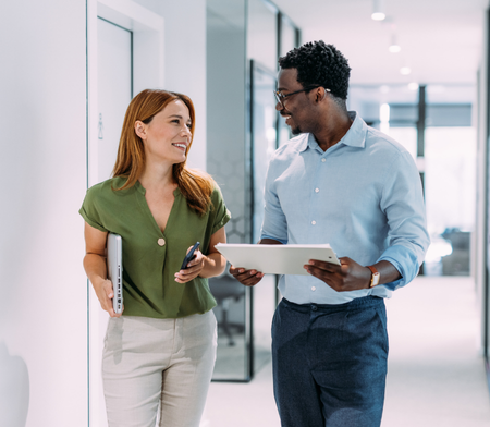 Male and female marketing colleague walking down a hall talking